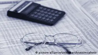 a calculator and a pair of glasses are placed on a newspaper page with market information