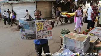A man reads a newspaper at a newsstand in Colombo, Sri Lanka