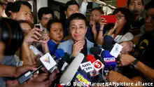 Journalist Maria Ressa surrounded by journalists with microphones and cellphones