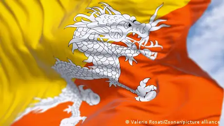 Picture of a Bhutanese flag that is half yellow and haly orange with a white dragon in the middle. 